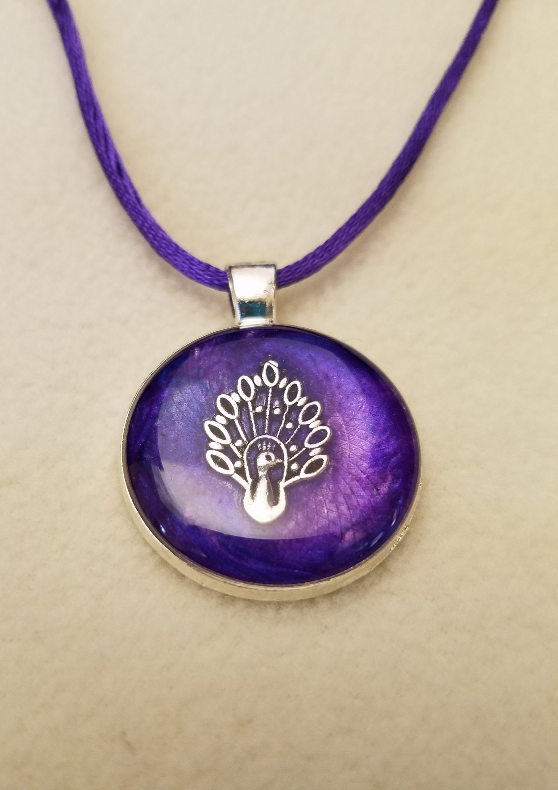 Silver Peacock in Purple Epoxy on a Round Silver Pendant on Purple Cord Necklace