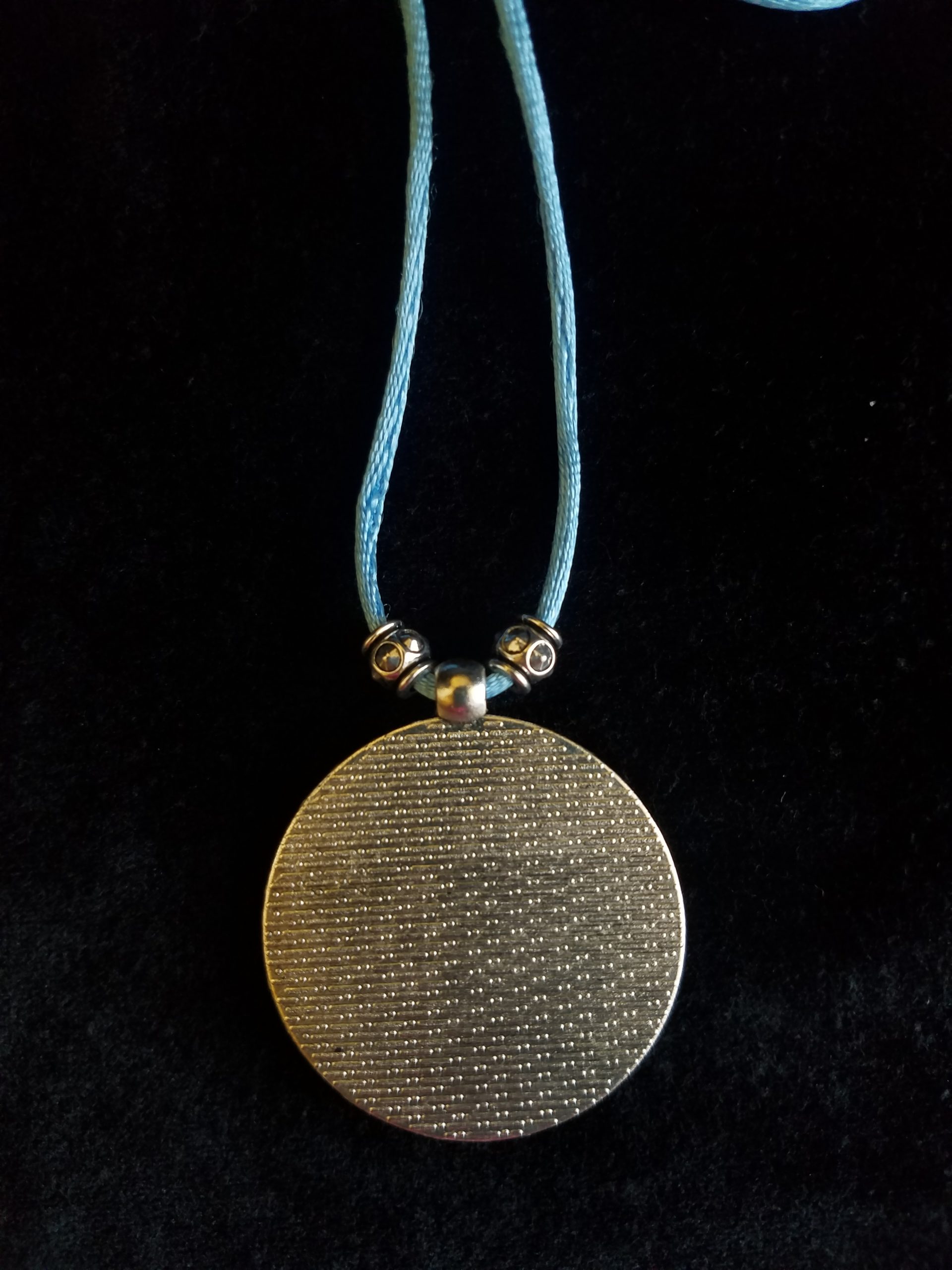 Back of Decorative Silver Pendant on Beaded Blue Cord Necklace