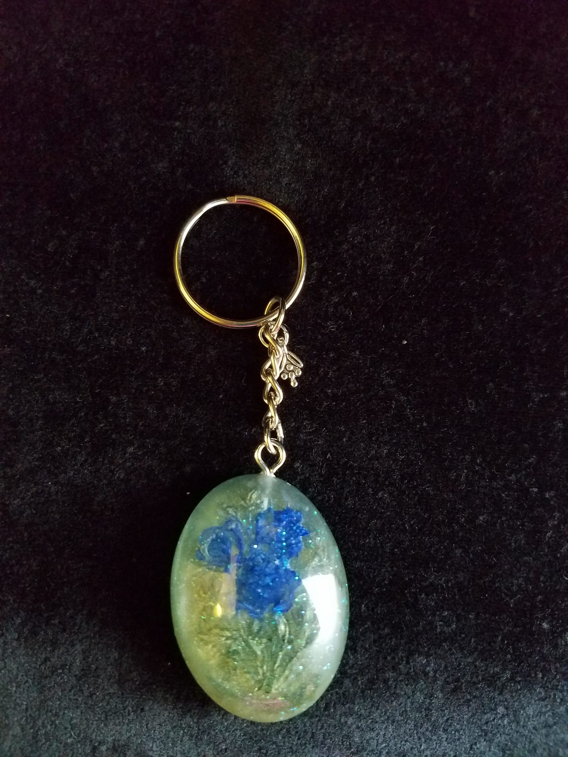 Oval Pendant Keychain Filled with Blue Flower Bouquet in Clear Glitter and Green Epoxy with Silver Flower Charm