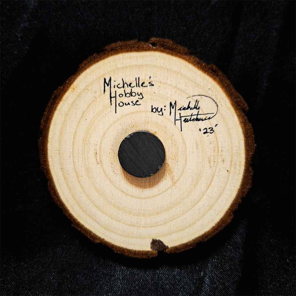 alt="View of the back artist and brand signatures on a 3 inch by 3 inch hand burned round wood slice magnet with bark edge.">