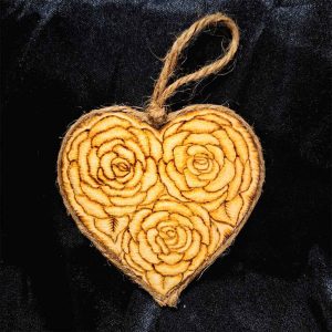 alt="3 inch by 3 inch heart shaped wood slice designed with 3 roses artwork hand burned finished with a brown twine outer edge with a loop for wall hanging.">