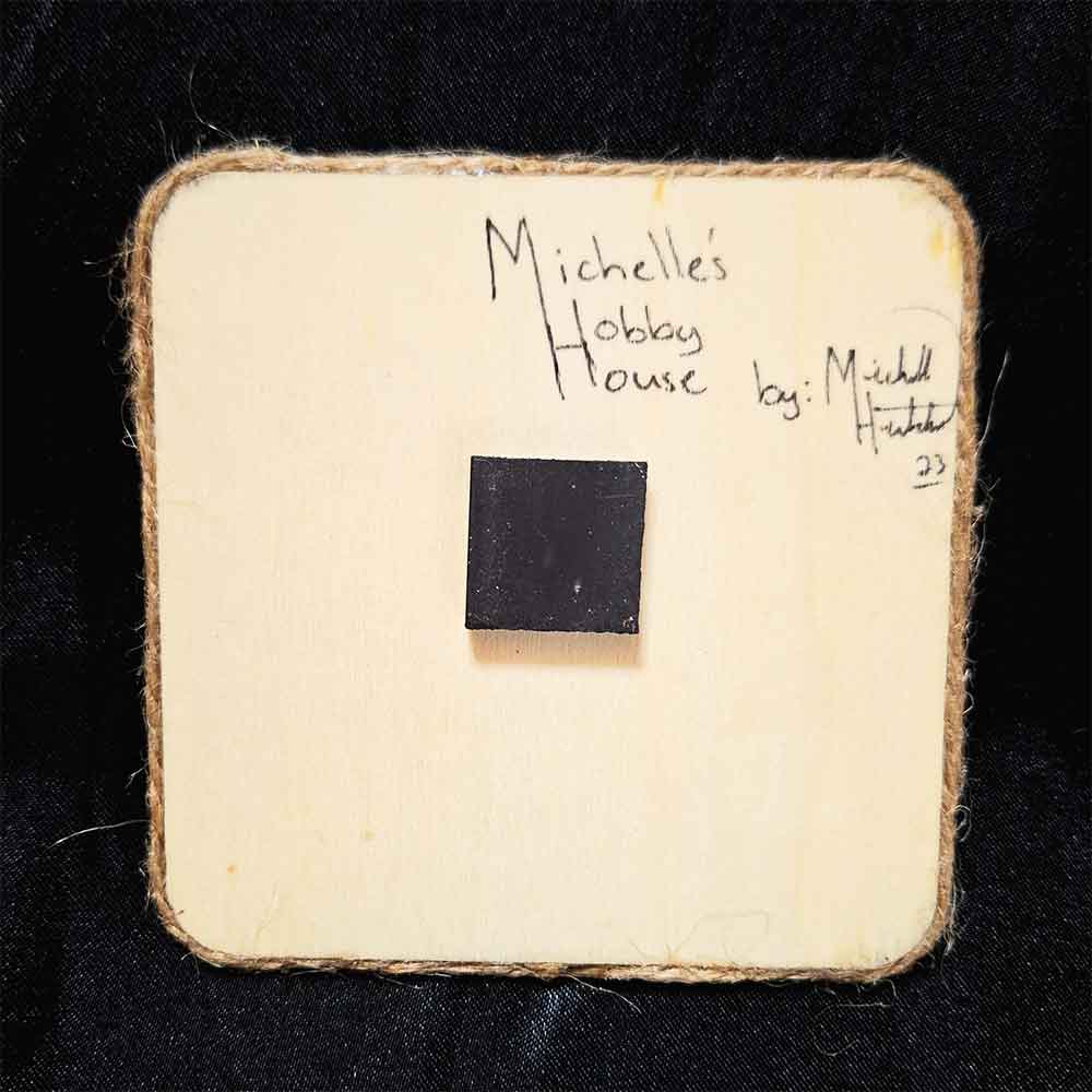 alt="View of the back artist and brand signatures on a 4 inch by 4 inch square wood slice magnet finished with a brown twine outer edge.">