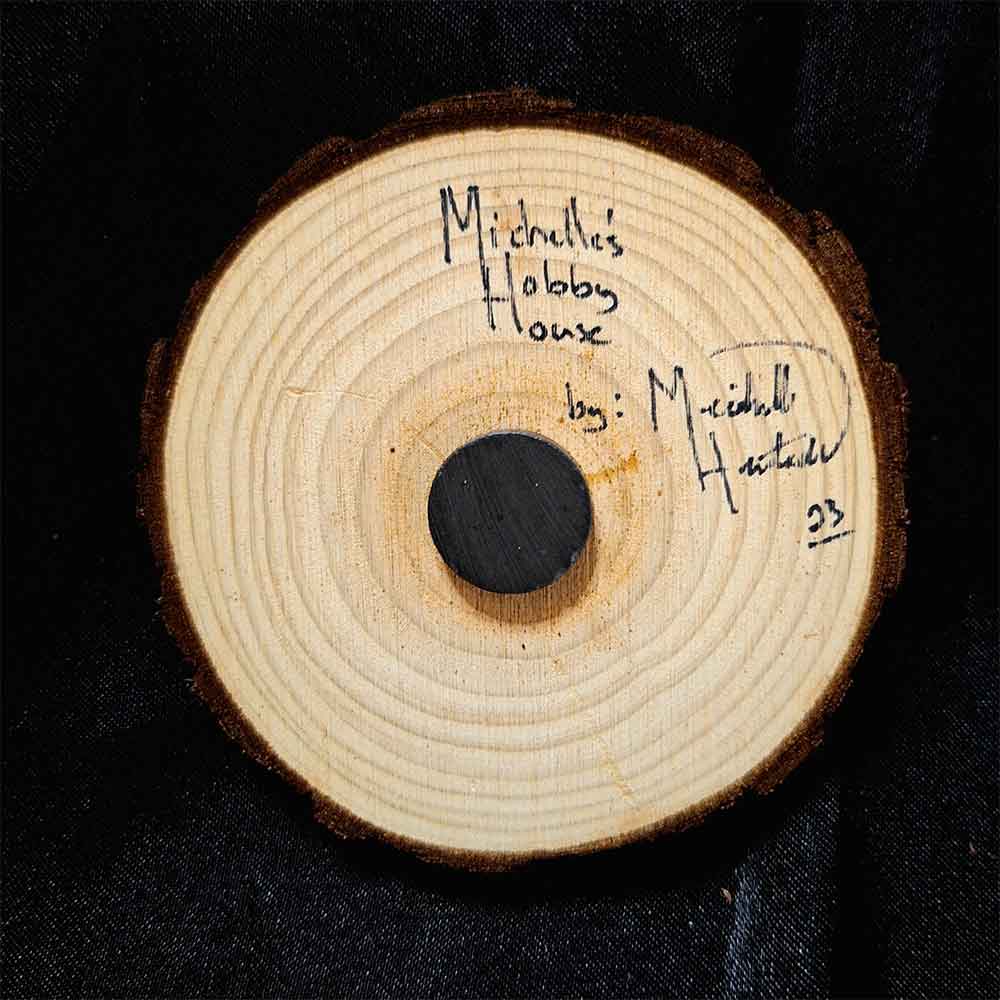 alt="View of the back artist and brand signatures on a 3 inch by 3 inch hand burned round wood slice magnet with bark edge.">