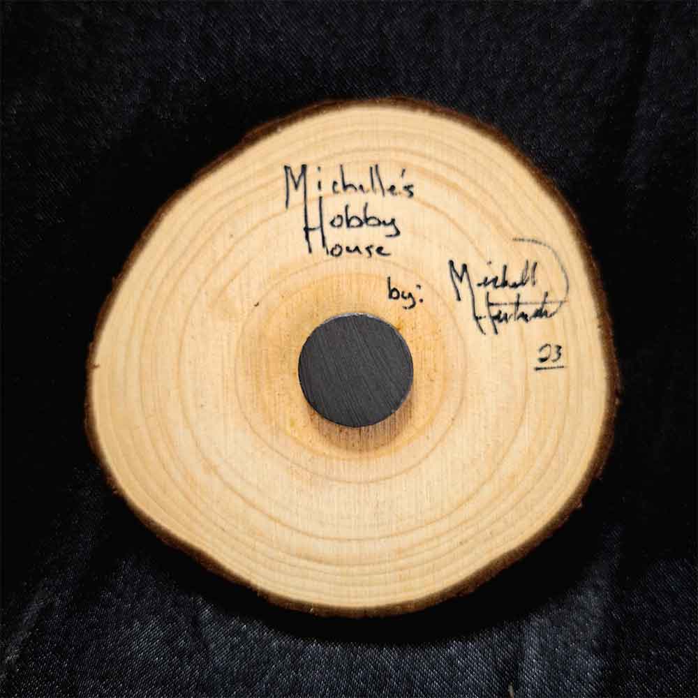 alt="View of the back artist and brand signatures on a 3 inch by 3 inch hand burned round wood slice magnet with bark edge.">
