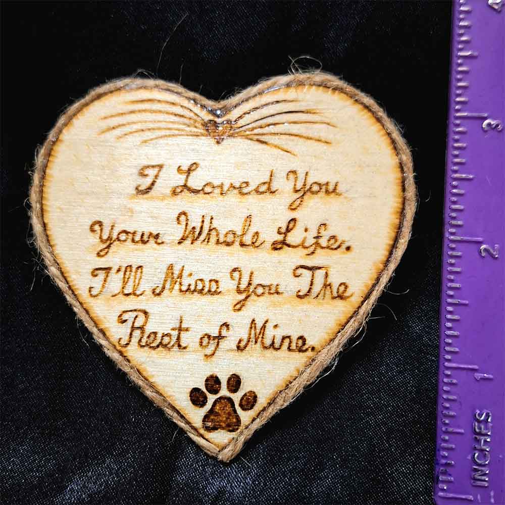 alt="Vertical ruler measuring a 3 inch by 3 inch hand burned heart shaped wood slice magnet with pet nose and whisker art at the top and poem that says 'I loved you your whole life, I'll miss you the rest of mine,' finished with a brown twine edge border.">