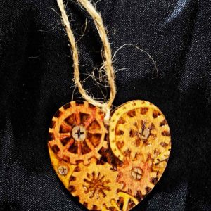 alt="Small 2 inch by 2 inch hand burned heart shaped wood slice with steampunk art with metallic painted gears finished with a brown twine loop for wall hanging">