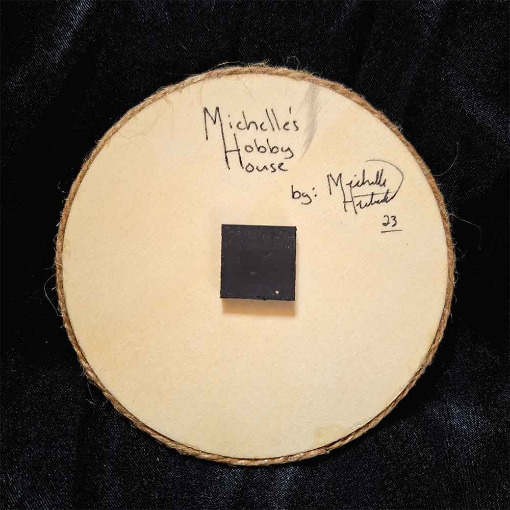 alt="View of the back artist and brand signatures on a 4 inch by 4 inch round wood slice magnet.">